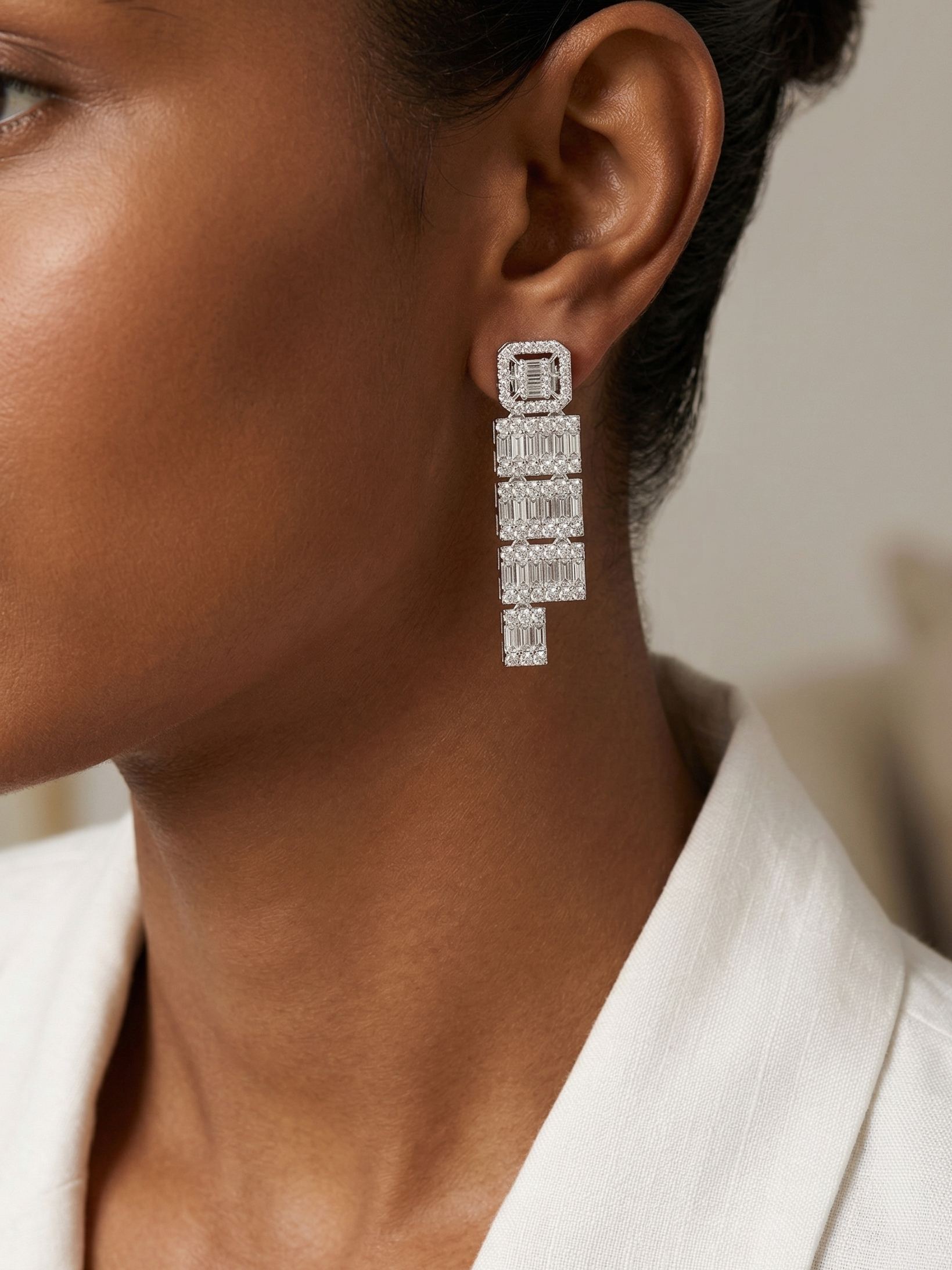 Close-up of a person wearing a diamond earring with a neutral background
