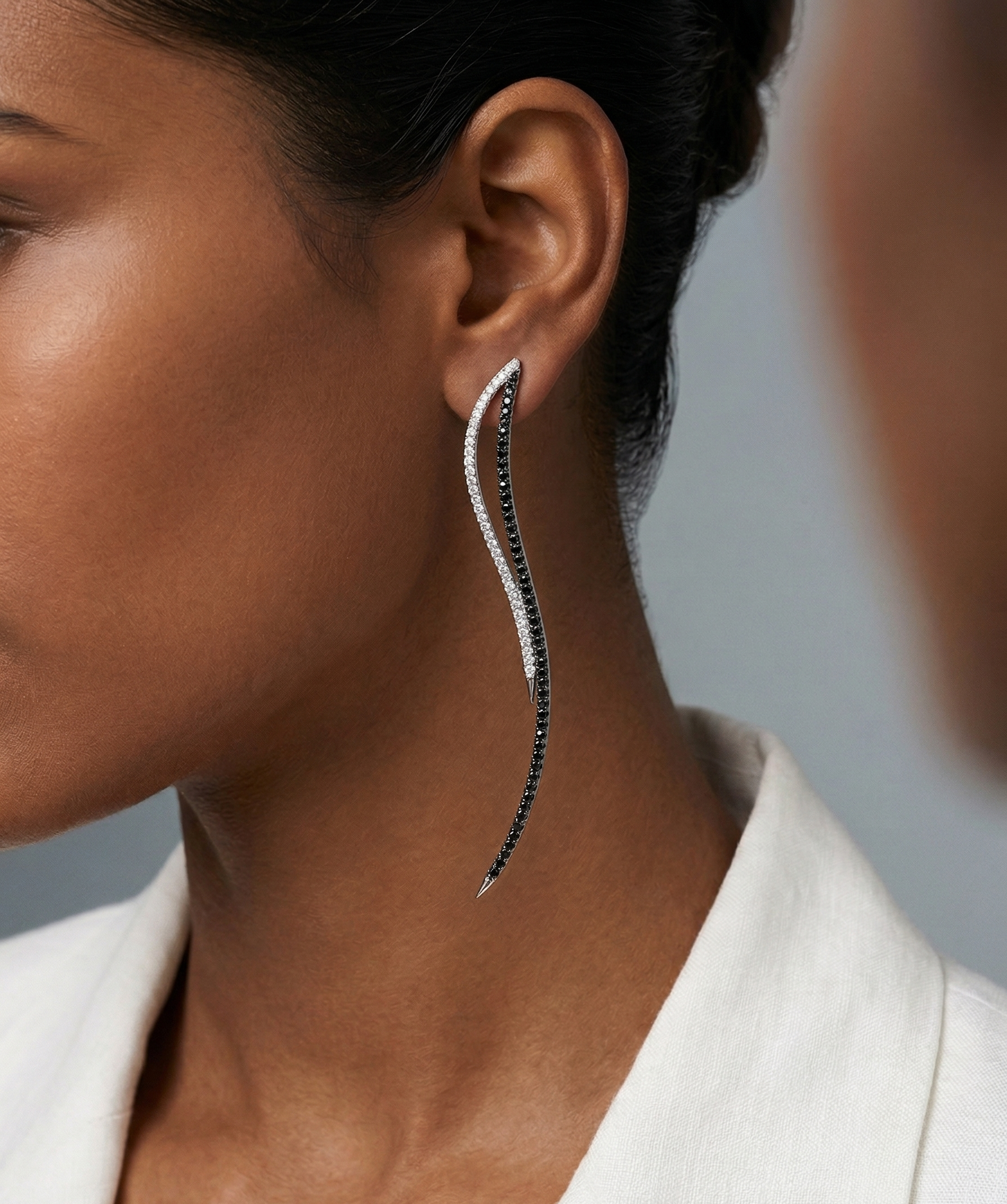 Close-up of a woman wearing a long, elegant earring with a neutral background