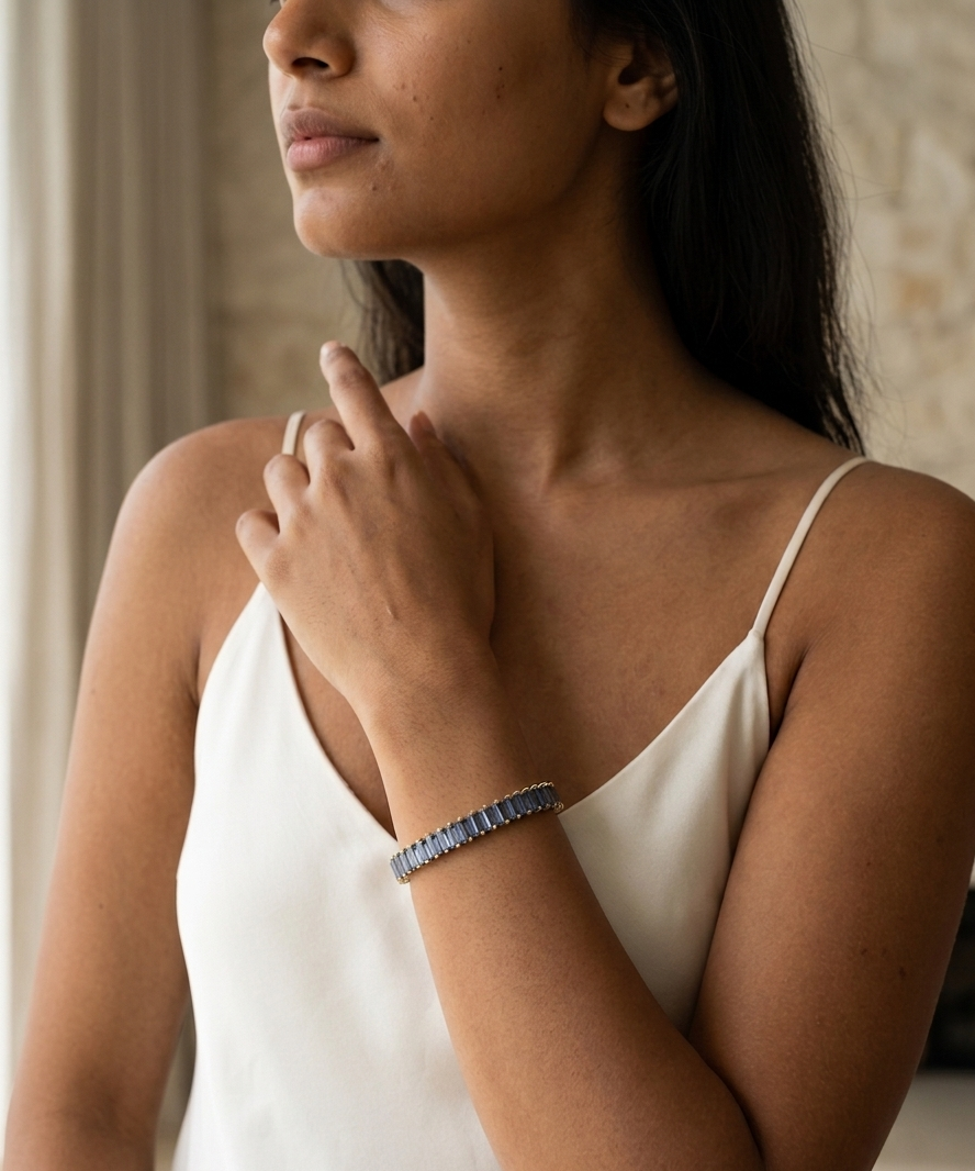 Woman wearing a white top and a bracelet, with a neutral background