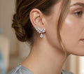 Close-up of a woman wearing a pair of diamond earrings with a neutral background
