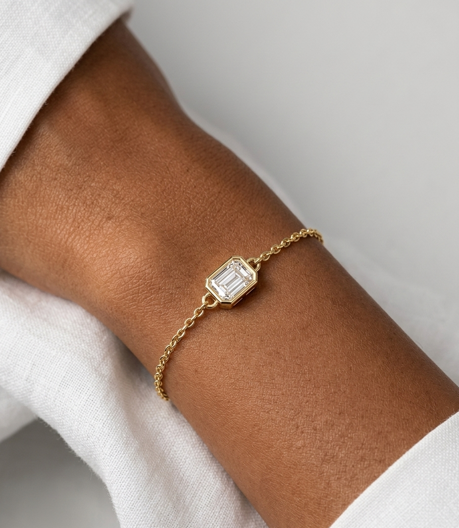 Gold bracelet with a diamond on a wrist against a neutral background
