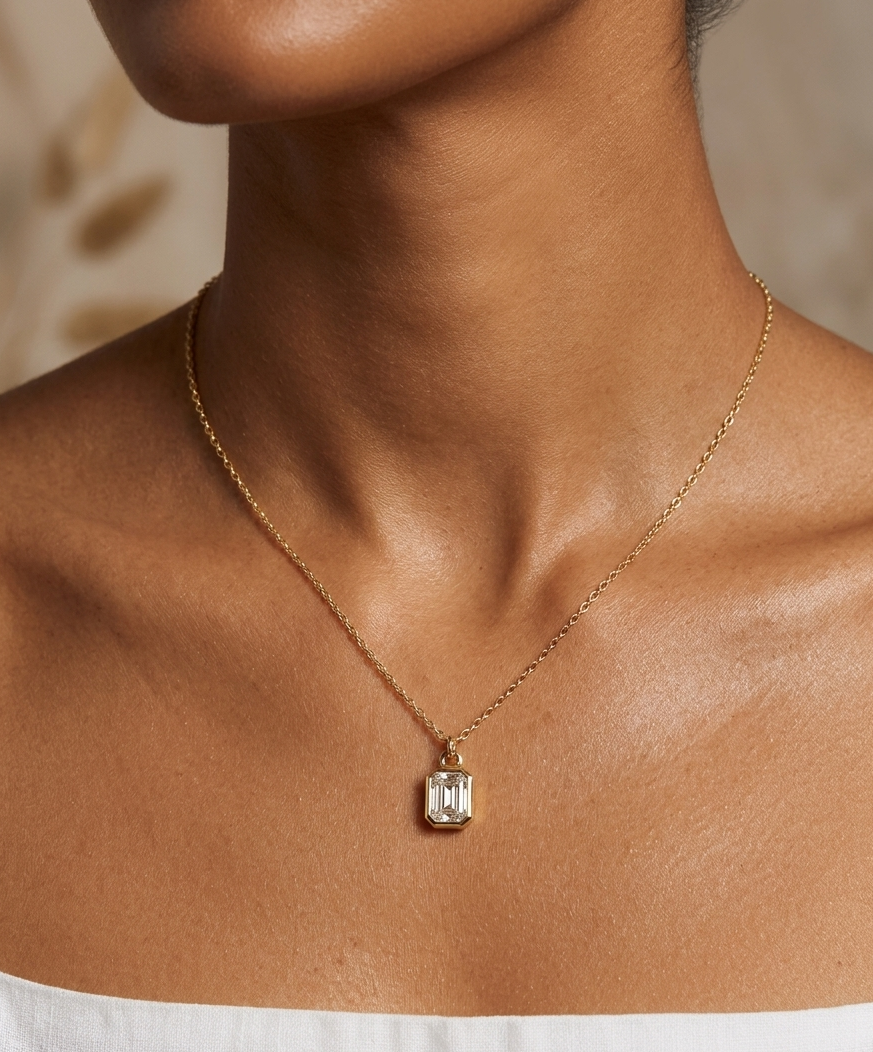 Gold necklace with a diamond pendant on a person wearing a white top.