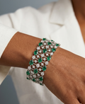 Bracelet with green gemstones on a wrist against a neutral background