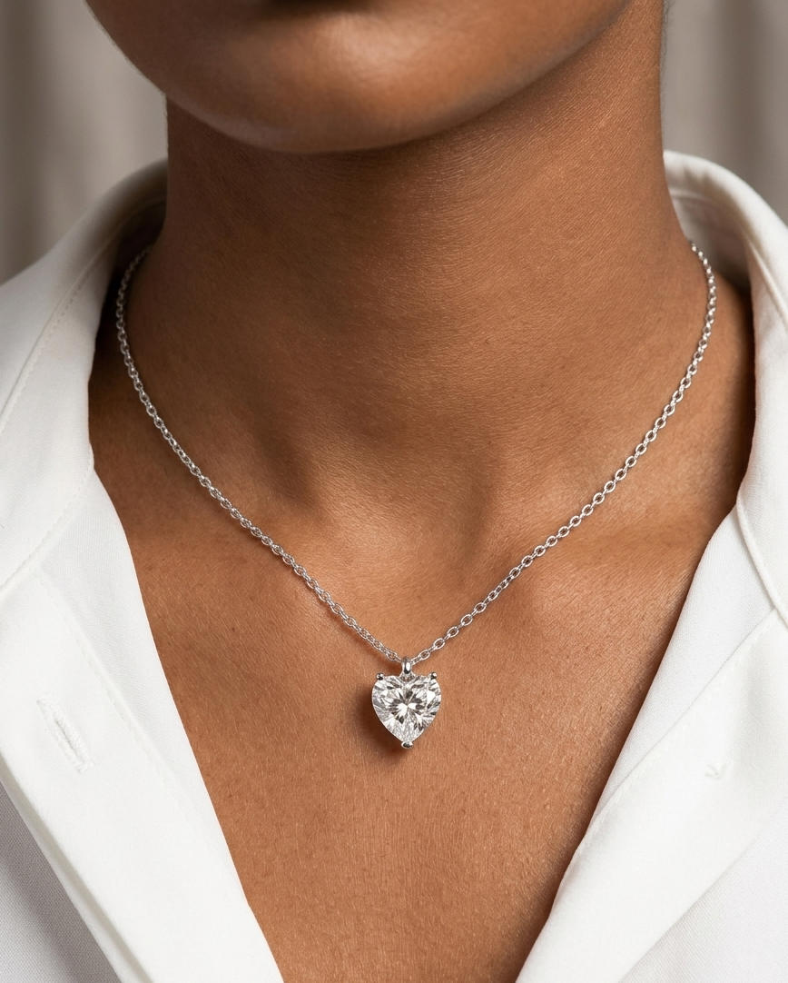 Heart-shaped diamond necklace on a person wearing a white shirt