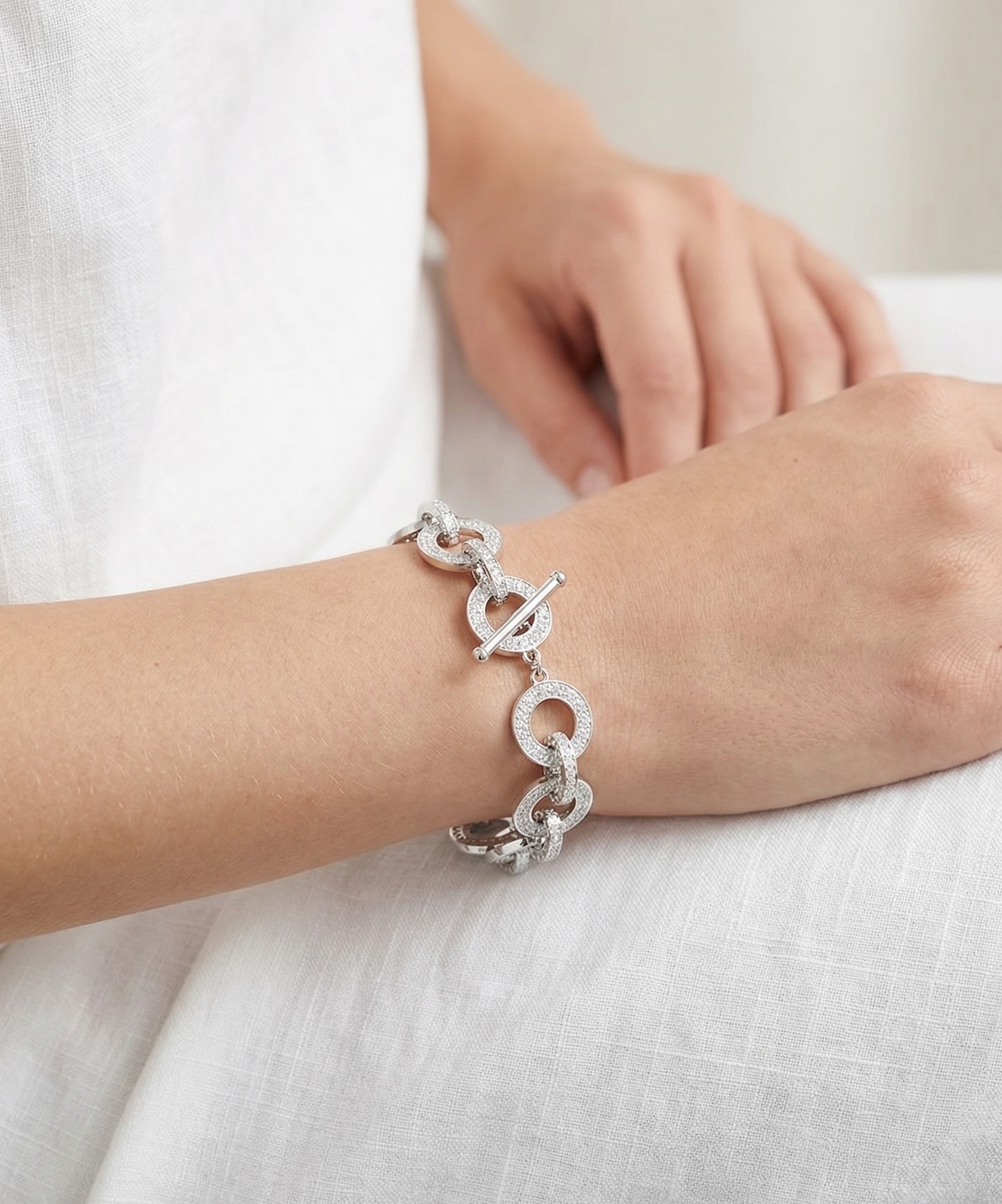 Silver chain bracelet on a wrist with a white background