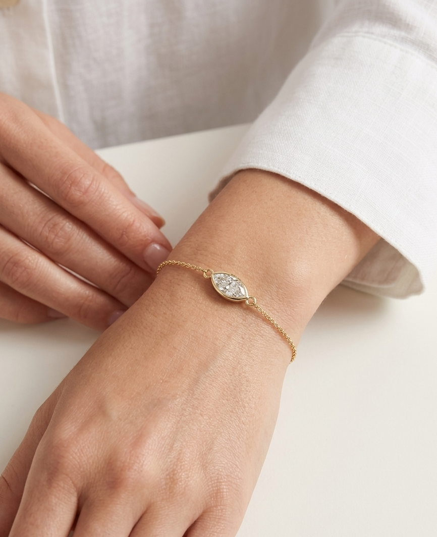 Gold bracelet with a diamond on a wrist against a white background