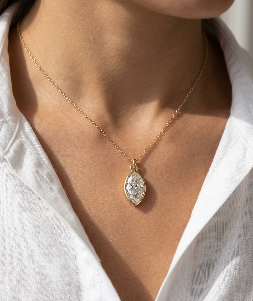 Gold necklace with a diamond pendant worn by a person in a white shirt.