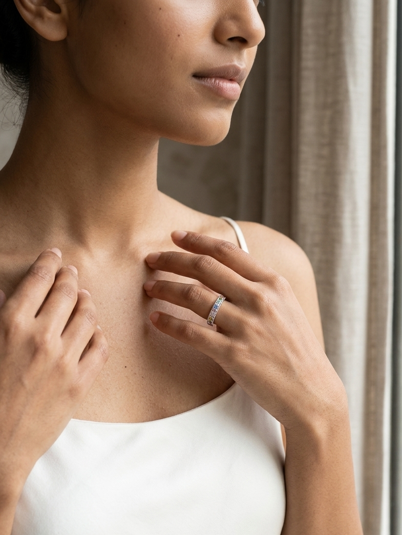 Woman wearing a wedding ring, standing in a softly lit room with curtains.