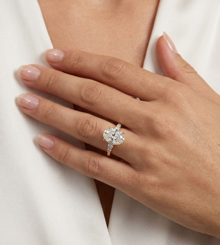 Hand wearing a diamond ring with a plain background