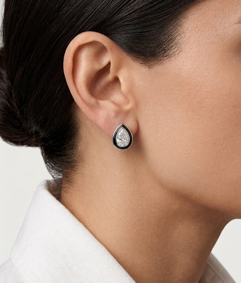 Teardrop-shaped earring worn by a person on a neutral background
