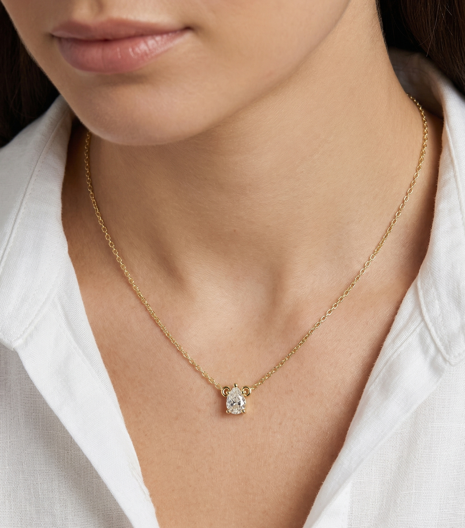 Gold necklace with a pendant worn by a person in a white shirt
