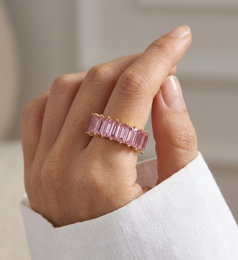 Hand wearing a pink gemstone ring with a blurred background