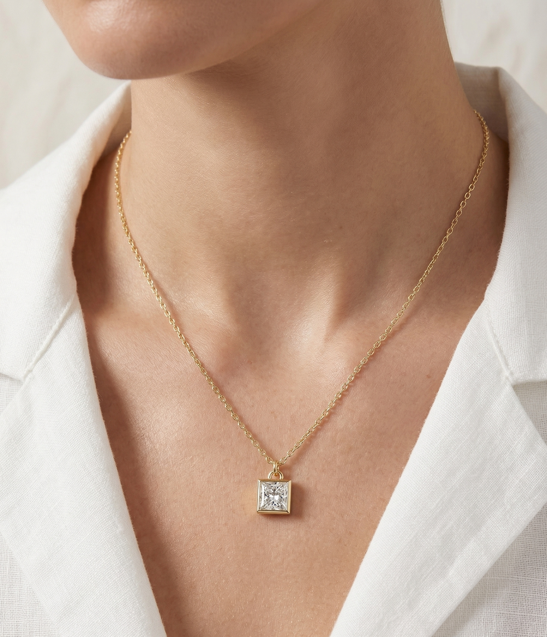 Gold necklace with a Prince Diamond pendant worn by a person in a white blazer.