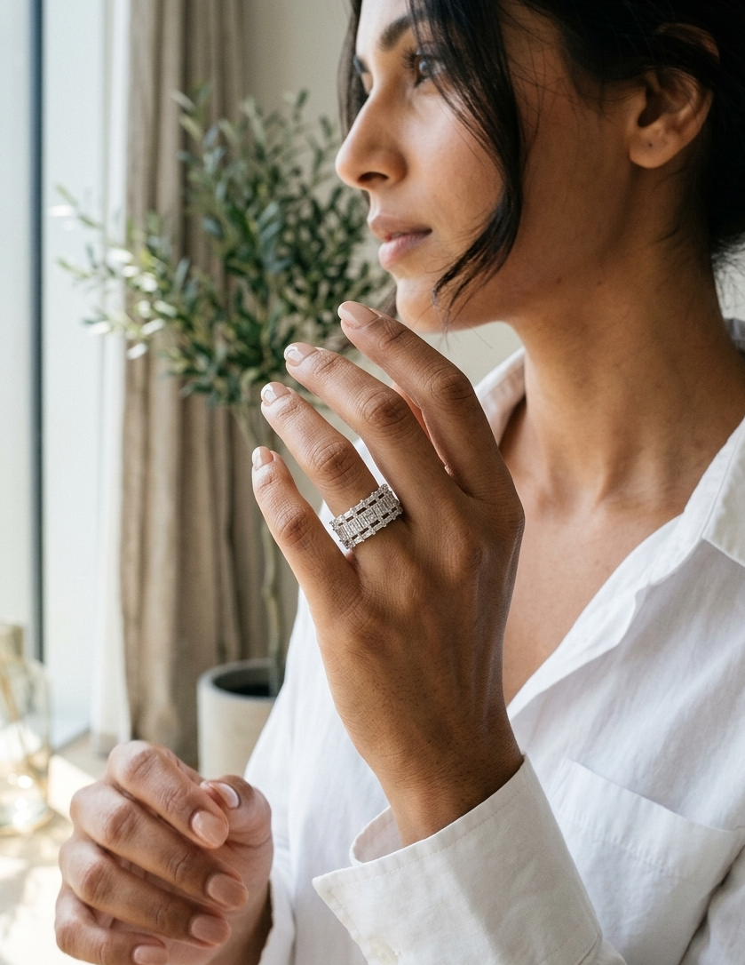 Woman wearing a silver ring in a softly lit room with a plant in the background