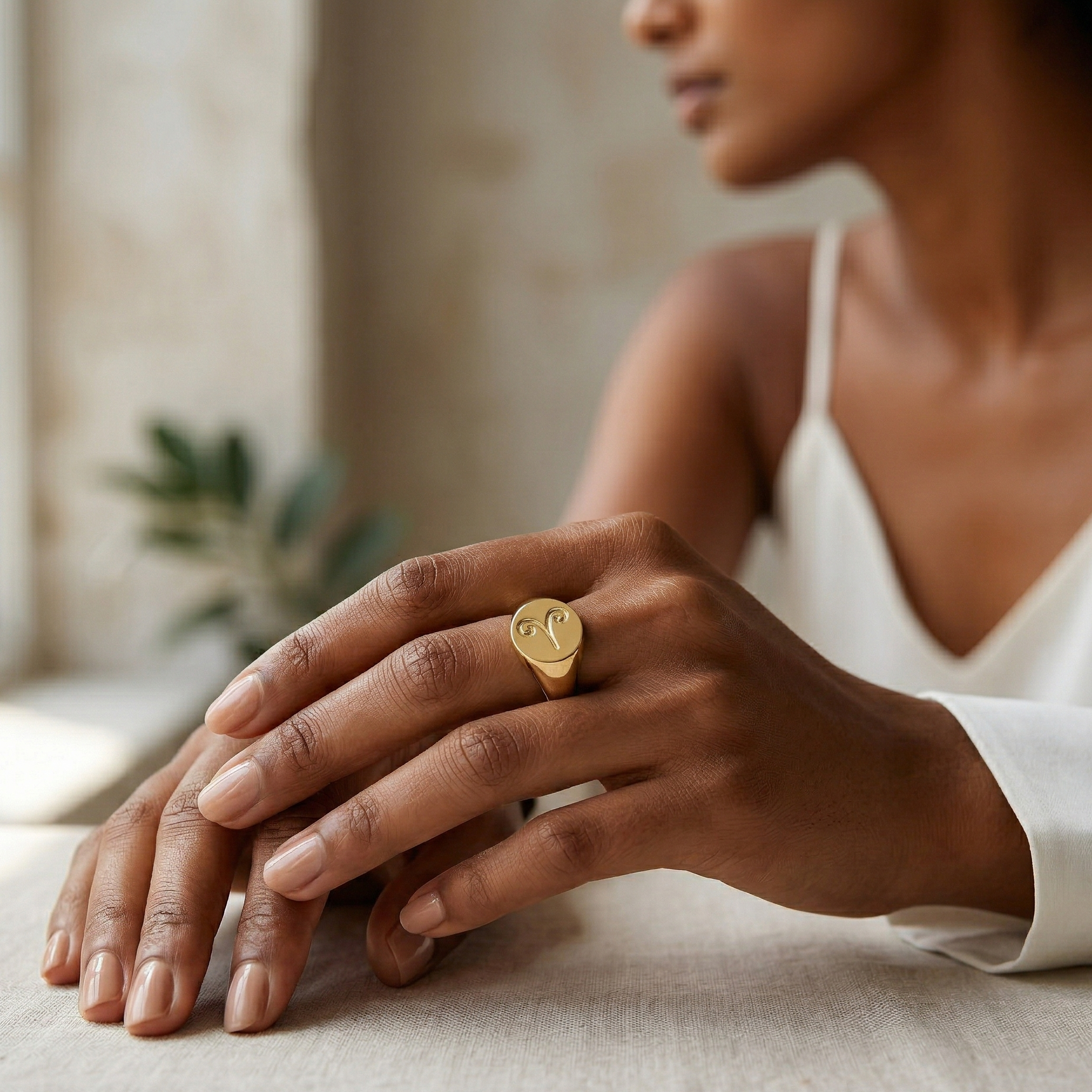 Person wearing a gold ring on a blurred indoor background