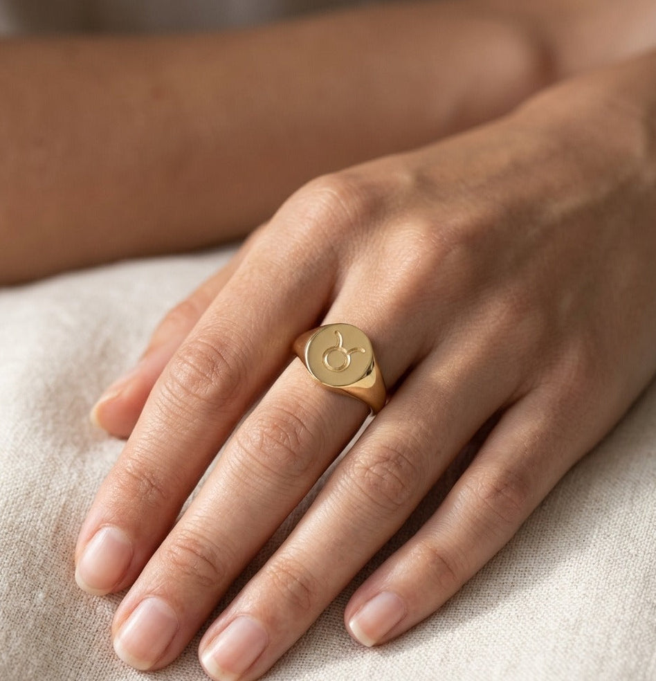 Gold ring on a person's finger against a neutral background