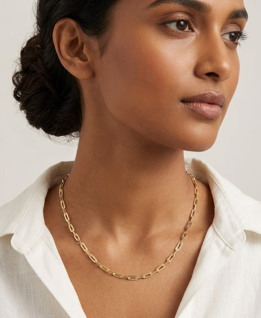 Woman wearing a gold chain necklace against a white background