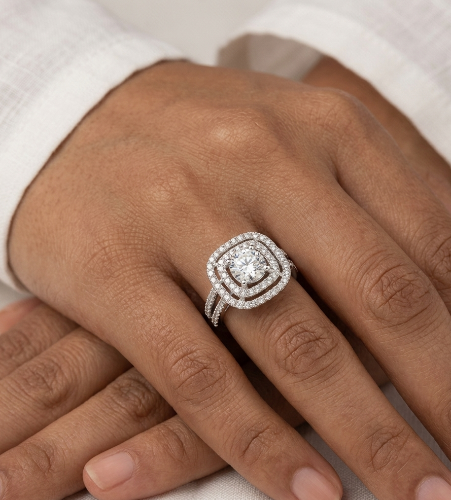 Silver ring with a diamond on a person's finger against a white background